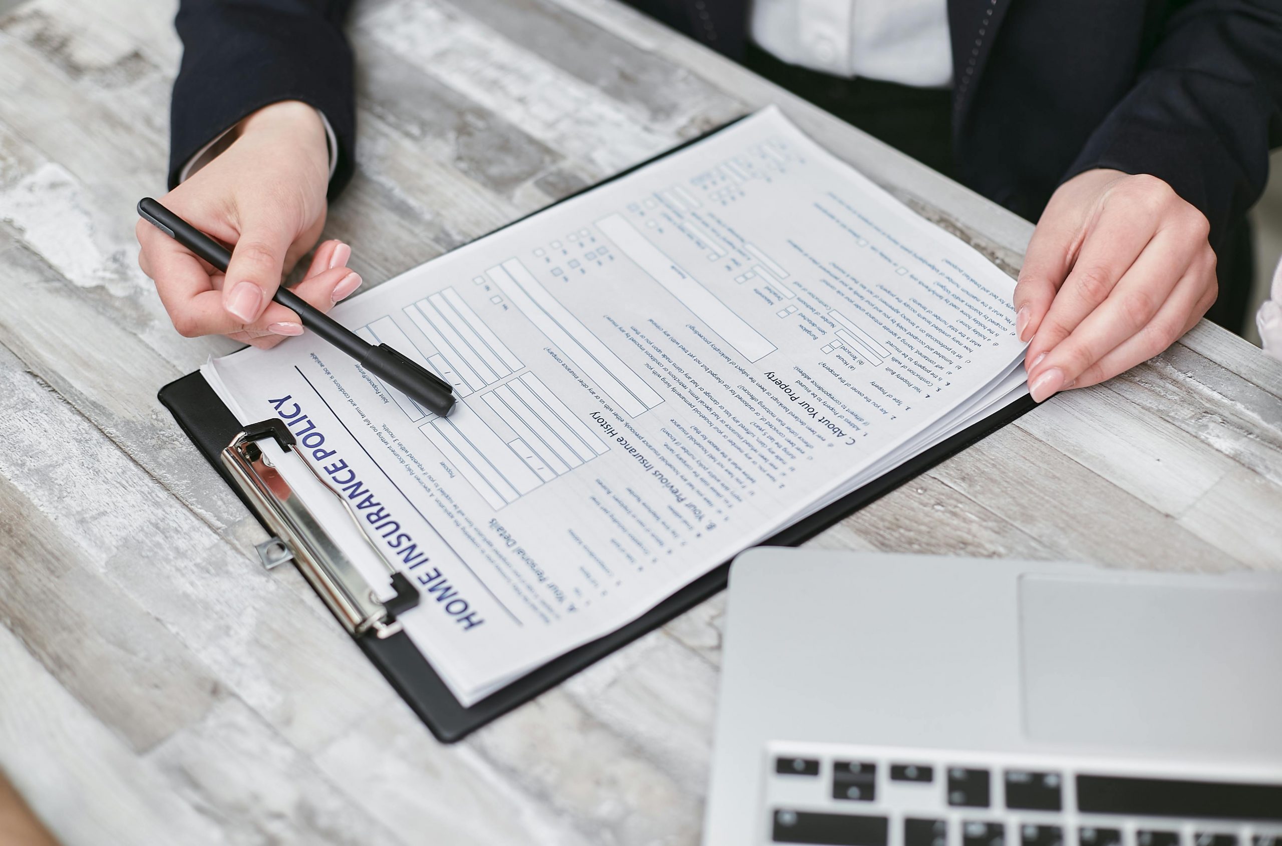 insurance agent using a pen to indicate details on a home insurance policy form